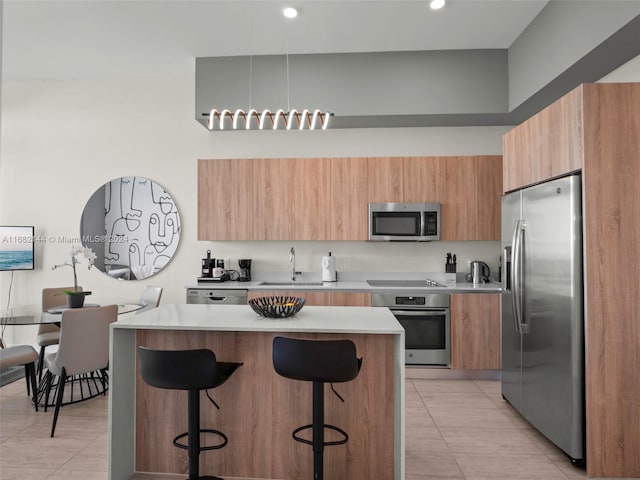 kitchen featuring a kitchen island, appliances with stainless steel finishes, light tile patterned floors, sink, and a kitchen breakfast bar