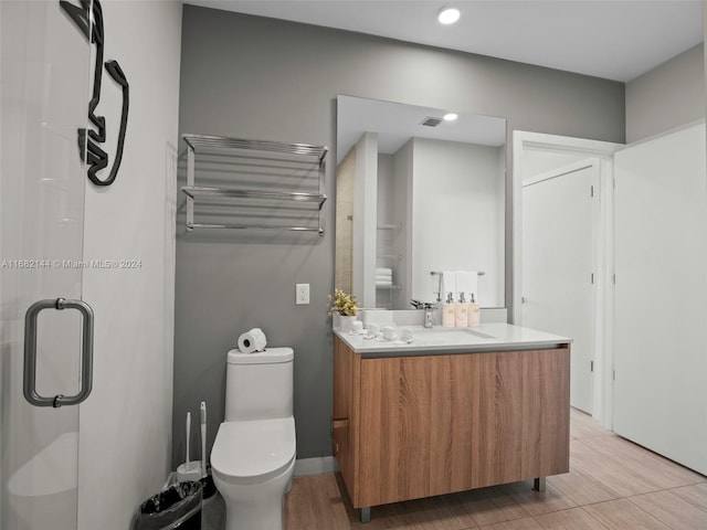 bathroom with radiator heating unit, wood-type flooring, vanity, toilet, and a shower with shower door