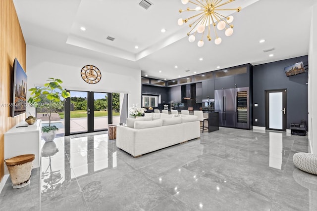 living room featuring a chandelier, french doors, a towering ceiling, and a tray ceiling