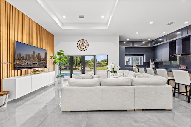 living room with a tray ceiling and wooden walls