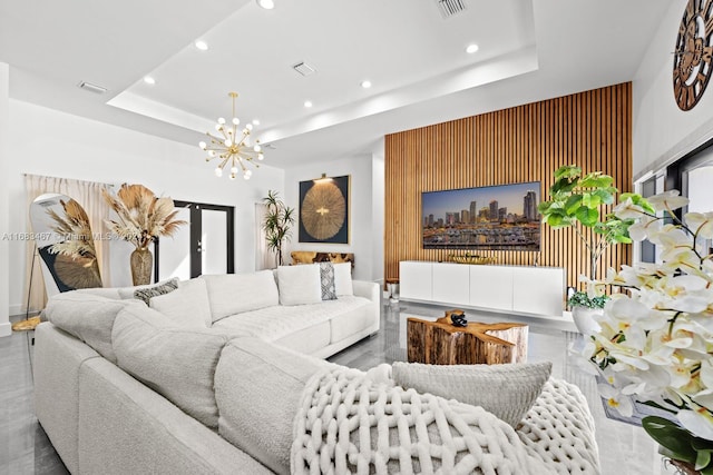 living room with a tray ceiling and a chandelier