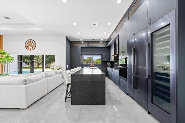 kitchen with sink, french doors, a kitchen bar, a center island with sink, and appliances with stainless steel finishes