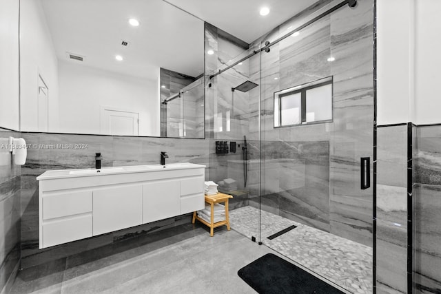 bathroom with vanity, a shower with shower door, and tile walls