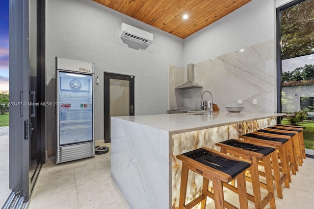 kitchen with an AC wall unit, sink, kitchen peninsula, wall chimney exhaust hood, and wood ceiling