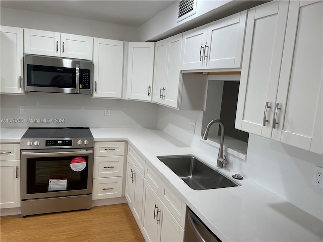 kitchen featuring white cabinetry, sink, light wood-type flooring, and appliances with stainless steel finishes