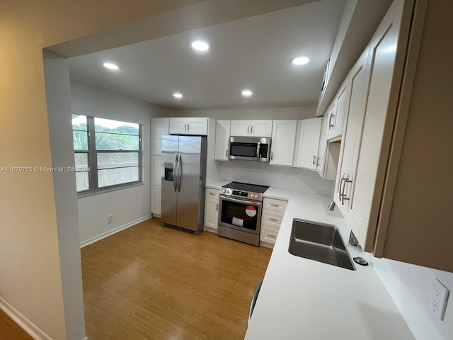 kitchen featuring light wood-type flooring, stainless steel appliances, white cabinetry, and sink