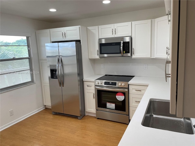 kitchen featuring white cabinets, light wood-type flooring, and appliances with stainless steel finishes