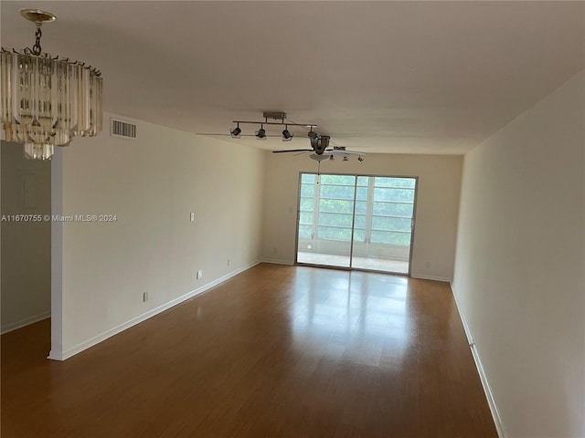 empty room with hardwood / wood-style floors and ceiling fan with notable chandelier