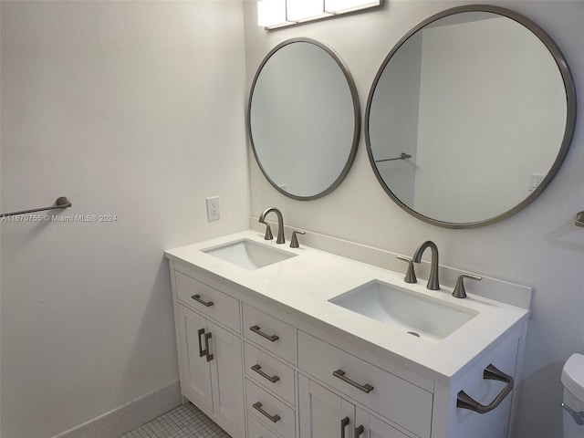 bathroom with toilet, vanity, and tile patterned floors