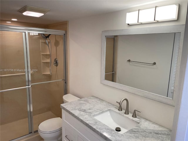 bathroom with vanity, toilet, and a shower with door