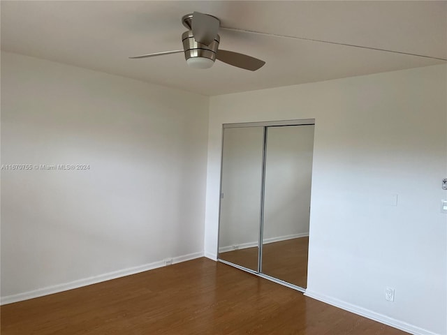 unfurnished bedroom featuring ceiling fan, a closet, and dark wood-type flooring