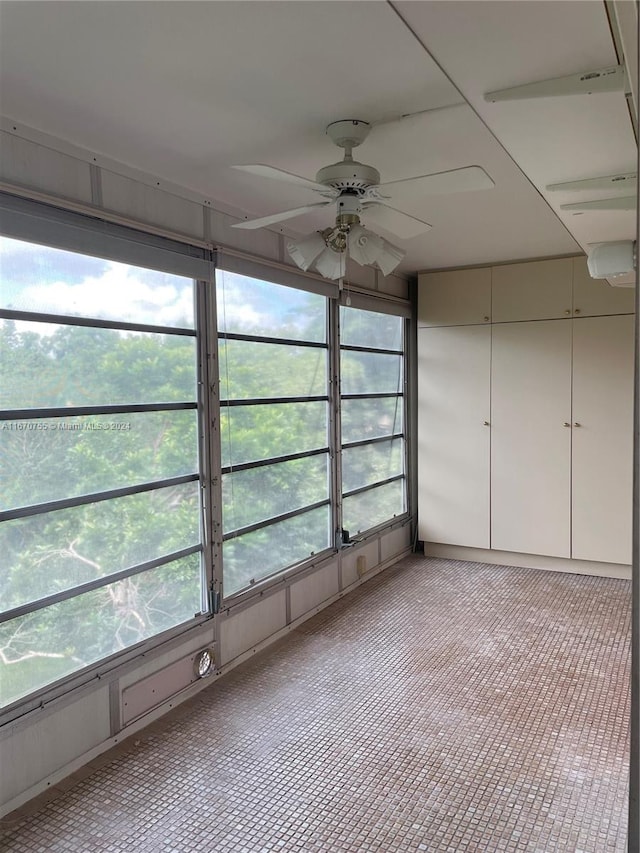 unfurnished sunroom featuring ceiling fan and plenty of natural light