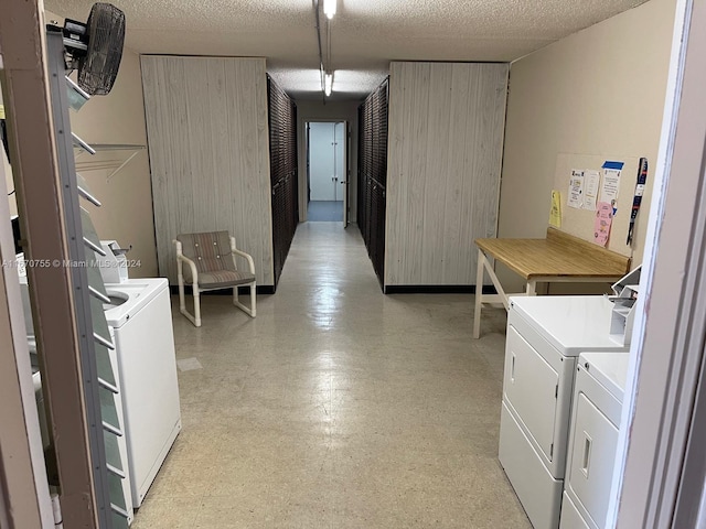 clothes washing area featuring a textured ceiling, separate washer and dryer, and wood walls