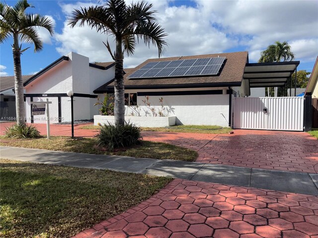 9230 SW 100th Ave Rd, Miami, FL 33176 - view of front facade with a gate, a fenced front yard, solar panels, stucco siding, and a shingled roof