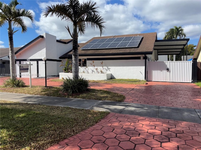 9230 SW 100th Ave Rd, Miami, FL 33176 - view of front of home with a gate, a fenced front yard, solar panels, stucco siding, and roof with shingles
