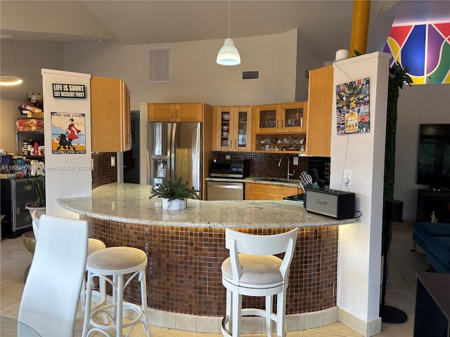 kitchen with kitchen peninsula, appliances with stainless steel finishes, light tile patterned floors, and sink