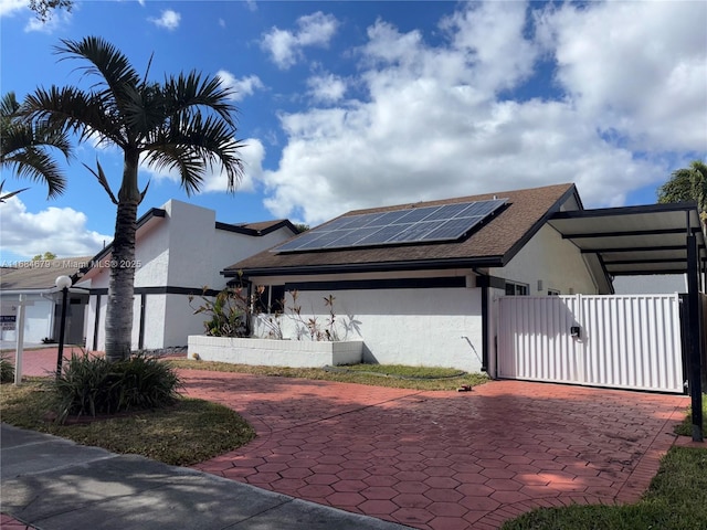 9230 SW 100th Ave Rd, Miami, FL 33176 - view of side of home with stucco siding, a fenced front yard, a gate, and roof mounted solar panels