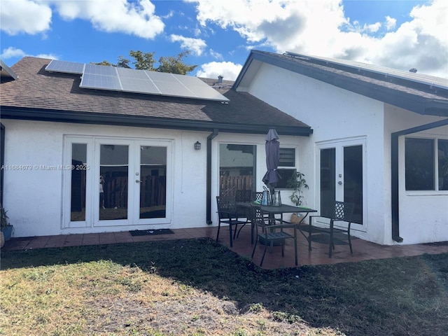 back of house featuring stucco siding, roof with shingles, a patio, french doors, and solar panels
