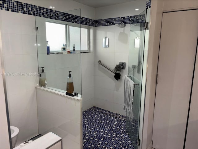 bathroom featuring tiled shower, tile patterned flooring, and tile walls