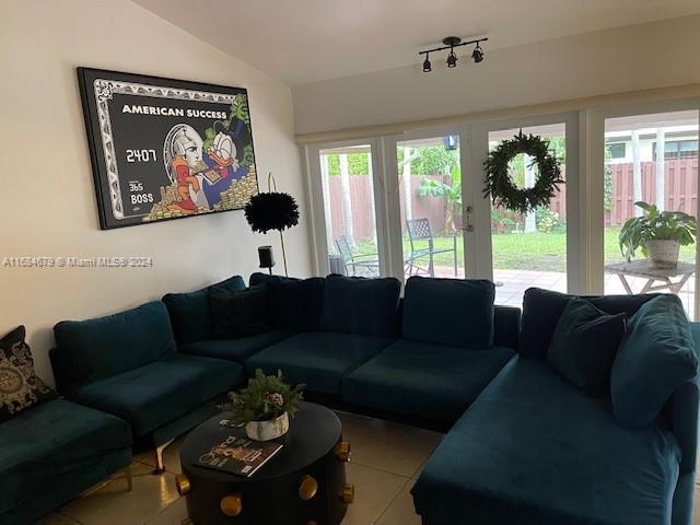 tiled living room featuring french doors and lofted ceiling