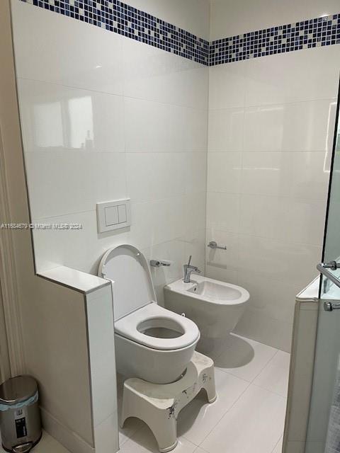 bathroom featuring tile patterned flooring, a bidet, toilet, and tile walls