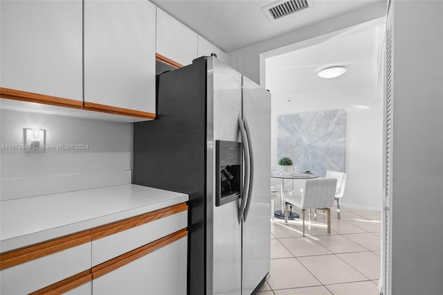 kitchen with white cabinetry, light tile patterned floors, and stainless steel fridge