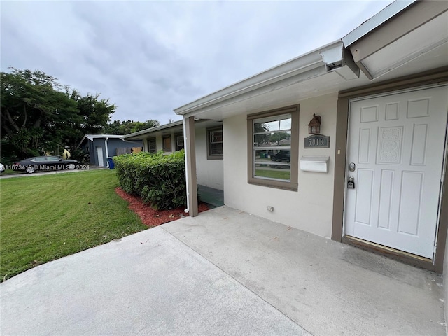 view of exterior entry with a patio and a lawn