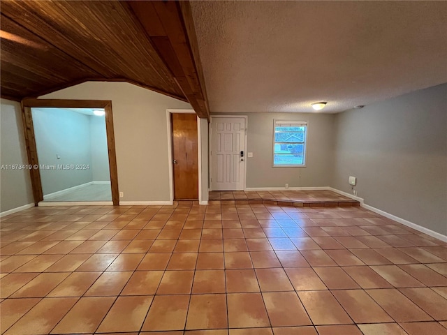 spare room featuring lofted ceiling, a textured ceiling, wood ceiling, and light tile patterned floors