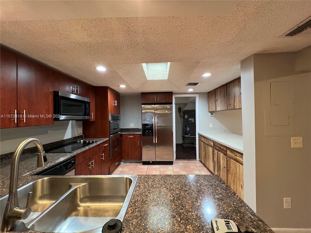 kitchen with light tile patterned floors, stainless steel appliances, a textured ceiling, and sink