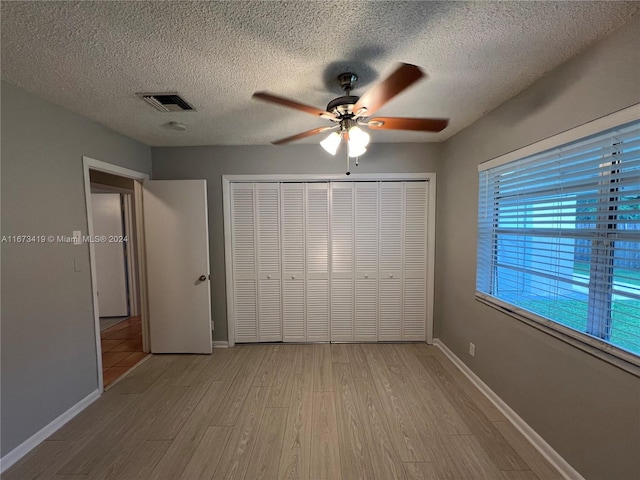 unfurnished bedroom with a closet, light hardwood / wood-style floors, a textured ceiling, and ceiling fan