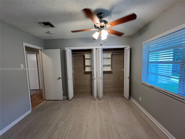 unfurnished bedroom featuring a closet, a textured ceiling, hardwood / wood-style flooring, and ceiling fan