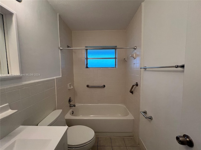 full bathroom with toilet, tiled shower / bath, vanity, tile walls, and a textured ceiling