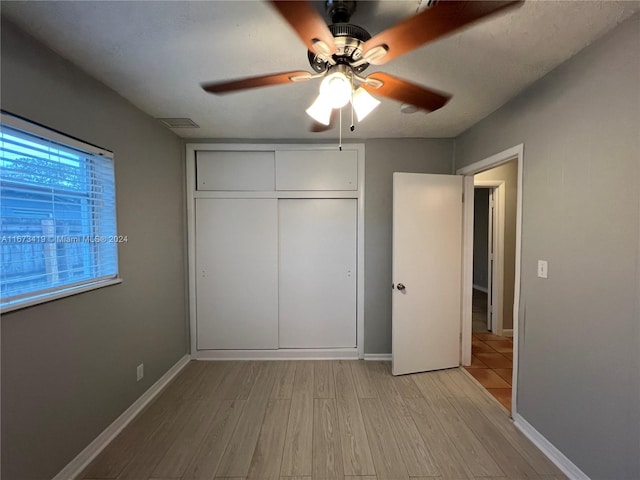 unfurnished bedroom featuring a closet, light hardwood / wood-style floors, a textured ceiling, and ceiling fan