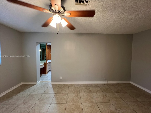 tiled spare room featuring a textured ceiling and ceiling fan