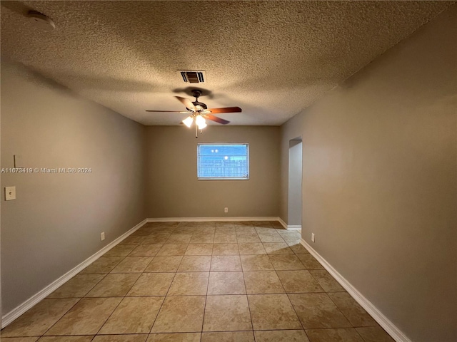 tiled spare room featuring a textured ceiling and ceiling fan