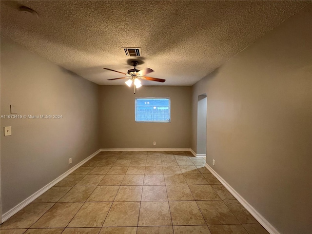 tiled spare room featuring a textured ceiling and ceiling fan