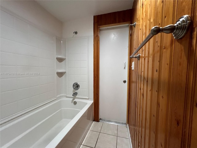 bathroom featuring wood walls, tiled shower / bath combo, and tile patterned flooring