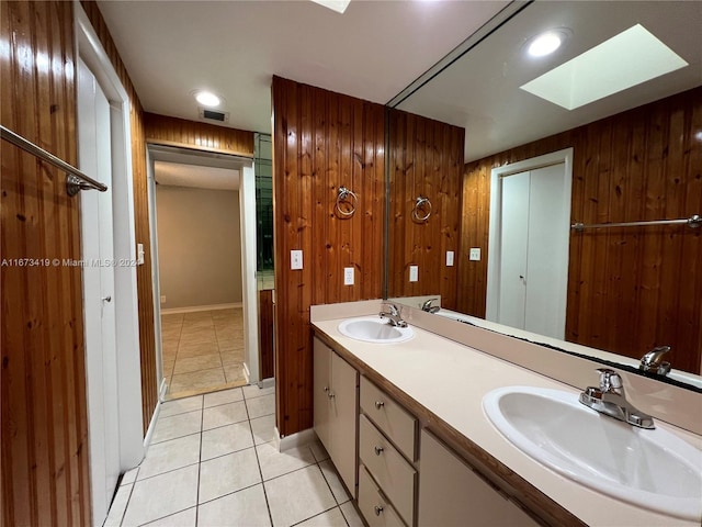 bathroom with vanity, tile patterned floors, a skylight, and wooden walls