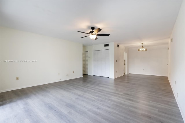 unfurnished room with hardwood / wood-style flooring and ceiling fan with notable chandelier