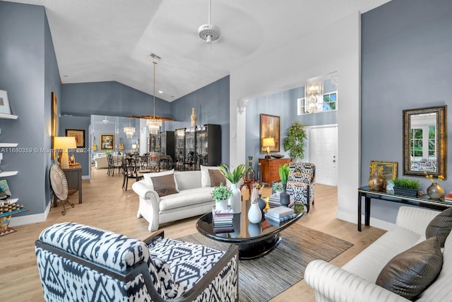 living room with light hardwood / wood-style flooring, high vaulted ceiling, and ceiling fan with notable chandelier