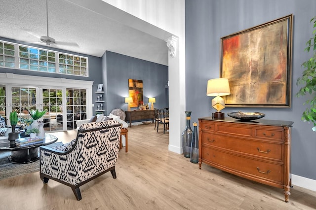 interior space featuring light hardwood / wood-style flooring, a textured ceiling, a towering ceiling, and ceiling fan