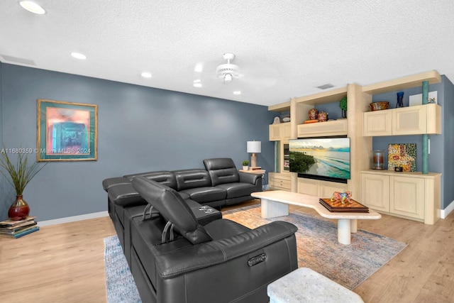 living room featuring a textured ceiling, light wood-type flooring, and ceiling fan