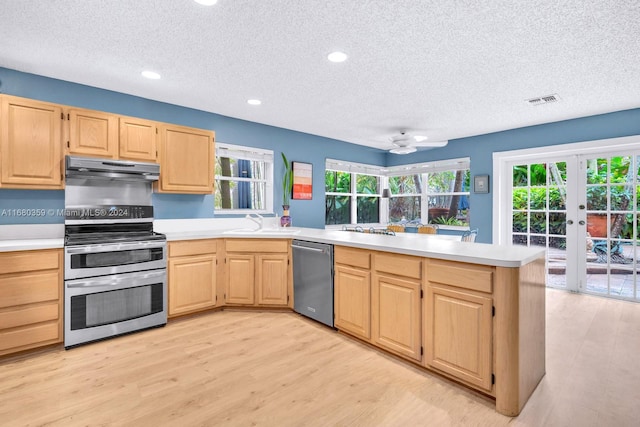 kitchen with light hardwood / wood-style floors, stainless steel appliances, light brown cabinetry, and ceiling fan