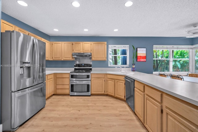 kitchen featuring appliances with stainless steel finishes, a textured ceiling, light brown cabinetry, light hardwood / wood-style floors, and sink