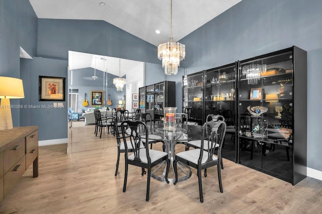 dining space with a chandelier, high vaulted ceiling, and light hardwood / wood-style floors