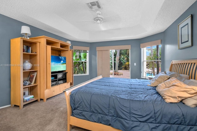 carpeted bedroom featuring a tray ceiling, a textured ceiling, access to outside, and ceiling fan