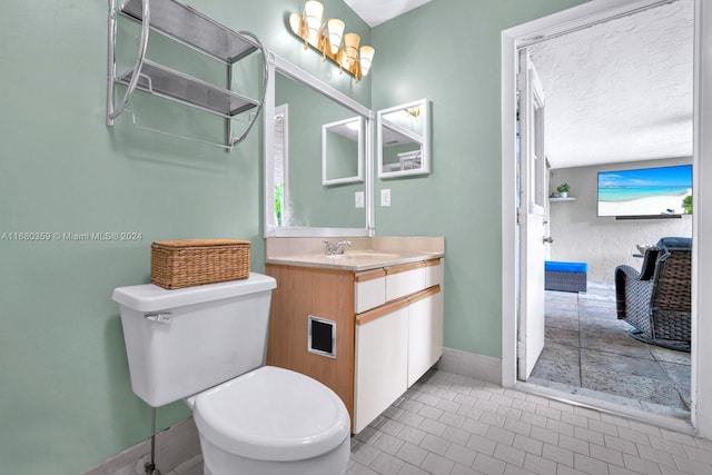 bathroom featuring vanity, toilet, tile patterned floors, and a textured ceiling