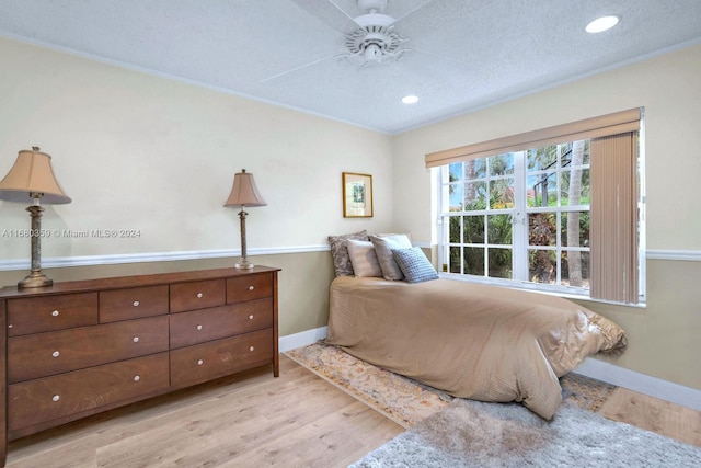 bedroom with ceiling fan, crown molding, a textured ceiling, and light wood-type flooring