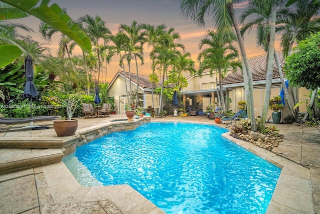 pool at dusk with a patio area