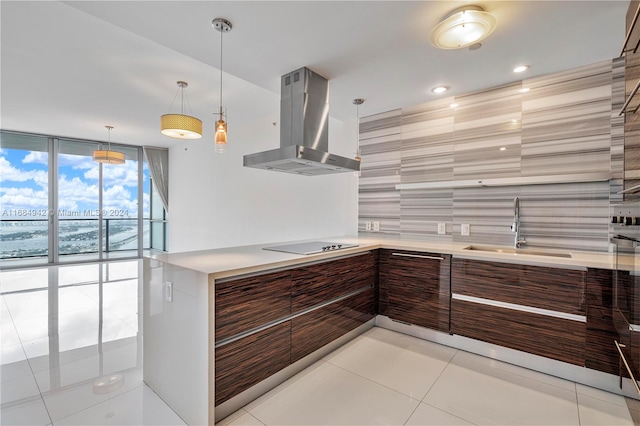 kitchen featuring light tile patterned flooring, sink, black electric cooktop, hanging light fixtures, and wall chimney exhaust hood